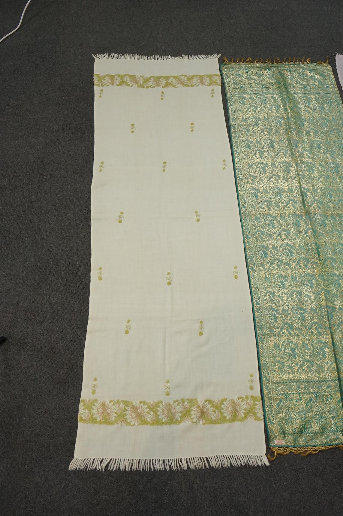 An Indian green and gold silk hand woven brocade stole, a cream pashmina embroidered stole and a similar finely woven and embroidered lilac stole (3). Brocade stole 38cm x 180cm., Condition - light stain to finely woven
